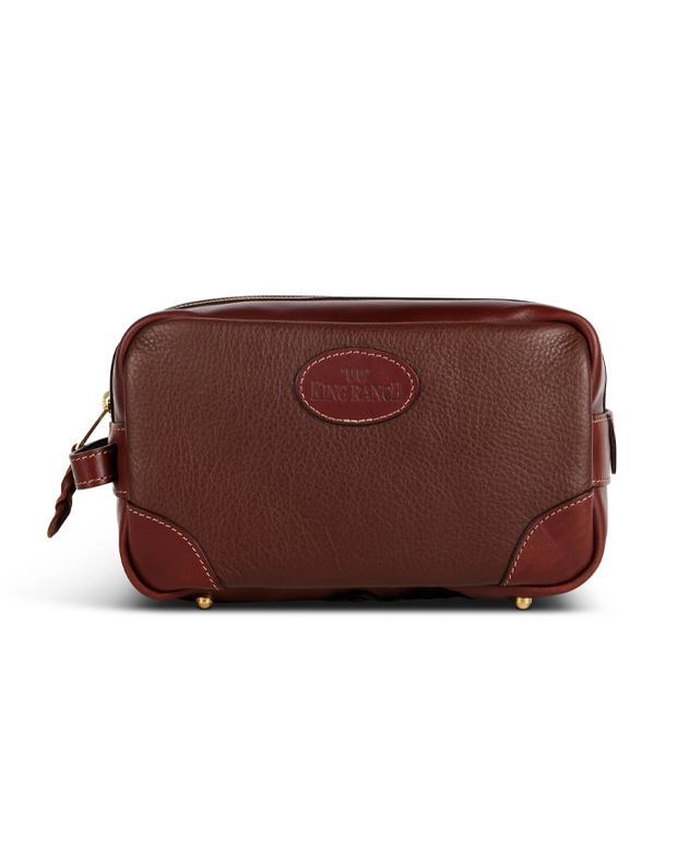  A luxurious brown leather toiletry bag with a stamped ‘King Ranch’ logo, featuring gold-tone hardware and a sturdy zipper, designed for both elegance and durability.