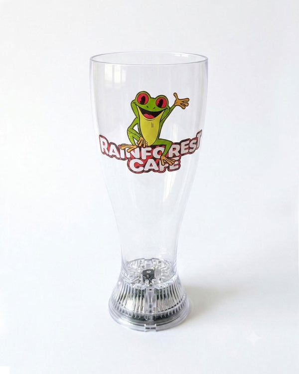 A clear plastic pint glass featuring a green tree frog graphic and the words 'RAINFOREST CAPE' in red and yellow, set against a plain white background.