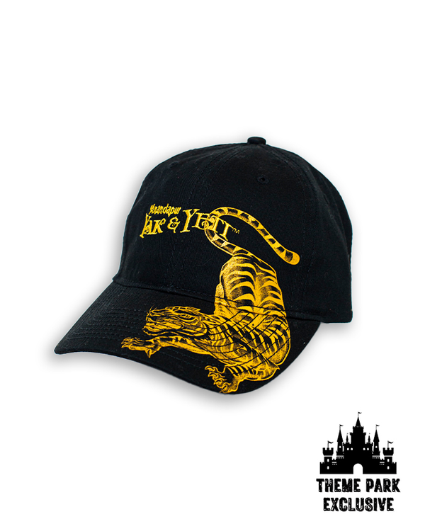 A black cap with a yellow tiger printed on one side, and "Yak & Yeti" embroidered in the center. The background is plain white with a Disney Castle logo at the bottom reading "THEME PARK EXCLUSIVE".