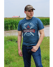 man standing in field wearing tee. Blue cotton tee with "Body By Barbeque" grill fork design above Saltgrass logo.