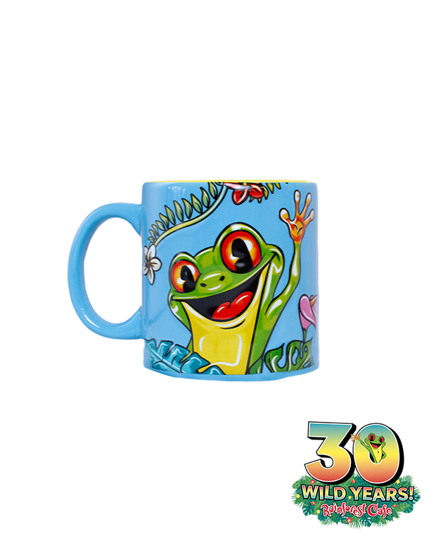 A blue mug with a handle on the left side, featuring an animated green frog with large, expressive eyes and an open mouth. The frog is surrounded by colorful tropical flowers and leaves, celebrating ‘30 WILD YEARS!’ at the Rainforest Cafe. Below the scene is the Rainforest Cafe logo with a smaller image of a green frog.