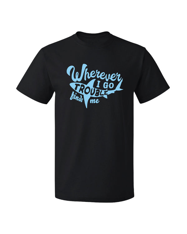 A black crewneck T-shirt that has a light blue shark silhouette on the center with text around it and inside it, reading "WHEREVER I GO TROUBLE FINDS ME". The background is plain white.