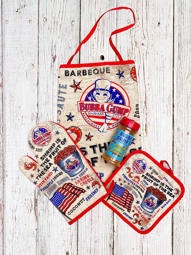 Bubba Gump grill set including Bubba Gump apron, oven mitt, hot pad, and Seafood Boil Seasoning placed in front of white wood background.
