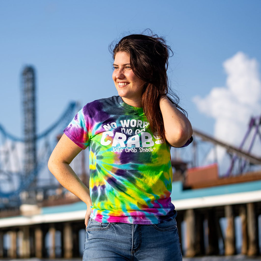 female model wearing tie dye shirt. background is of a pier.