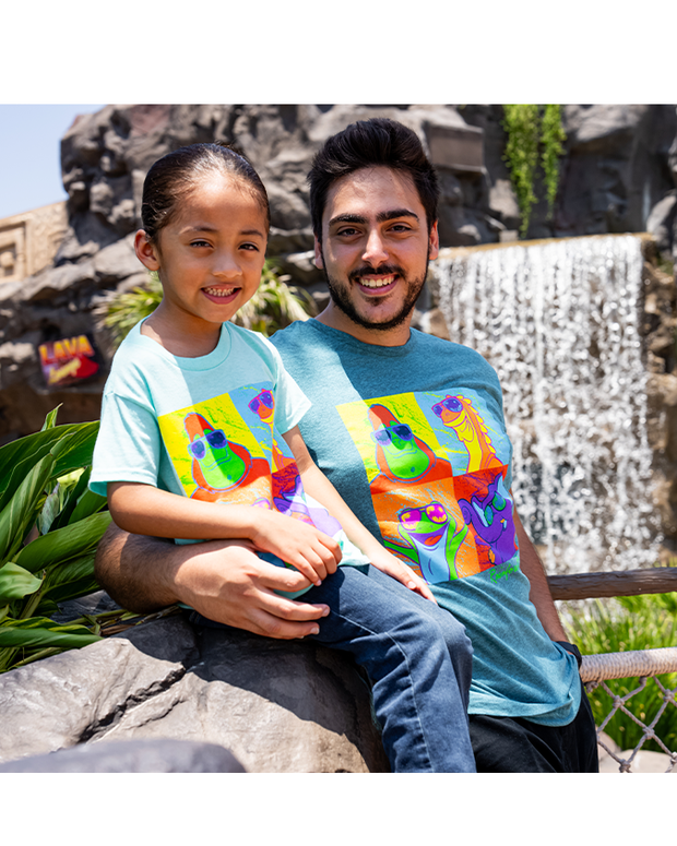 man & boy model in front of a waterfall. man has his arm wrapped around the boy who is sitting on a stone wall.