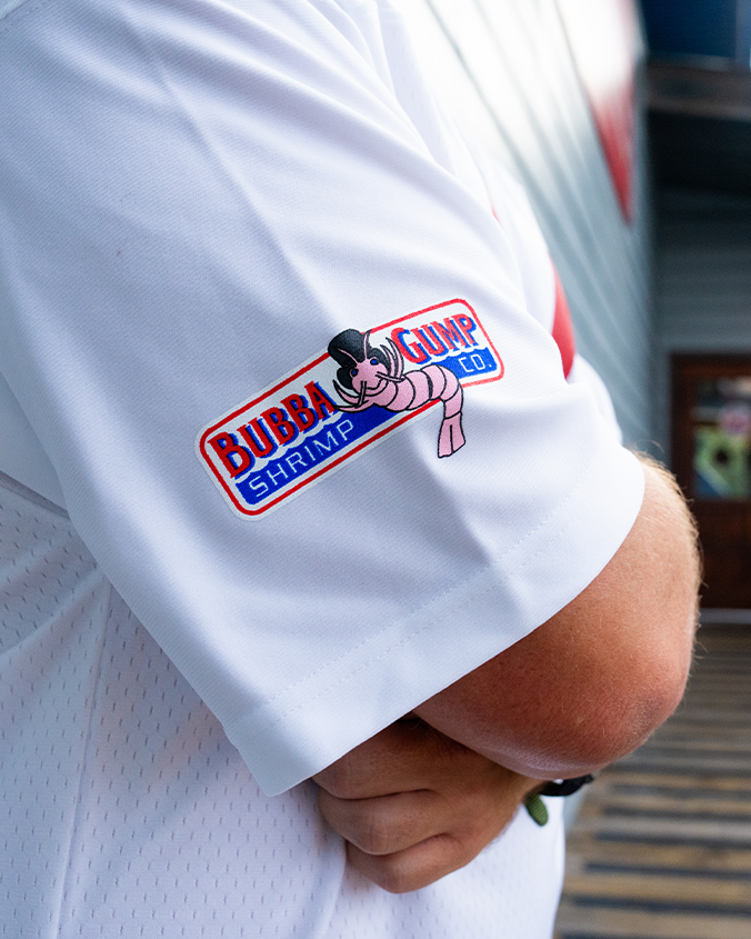 Close-up of a white shirt sleeve featuring the colorful "Bubba Gump Shrimp Co." logo with a cartoon shrimp wearing a hat.