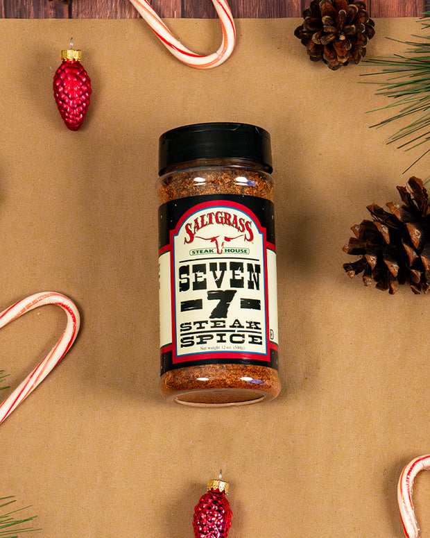 7 spice seasoning laid on a brown piece of paper, adorned with red ornaments, pinecones and candy canes around.