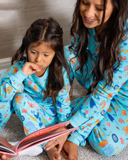 Mother reading book with daughter while wearing Under the Sea PJ set and there is a red tag in corner that says "Free Shipping"