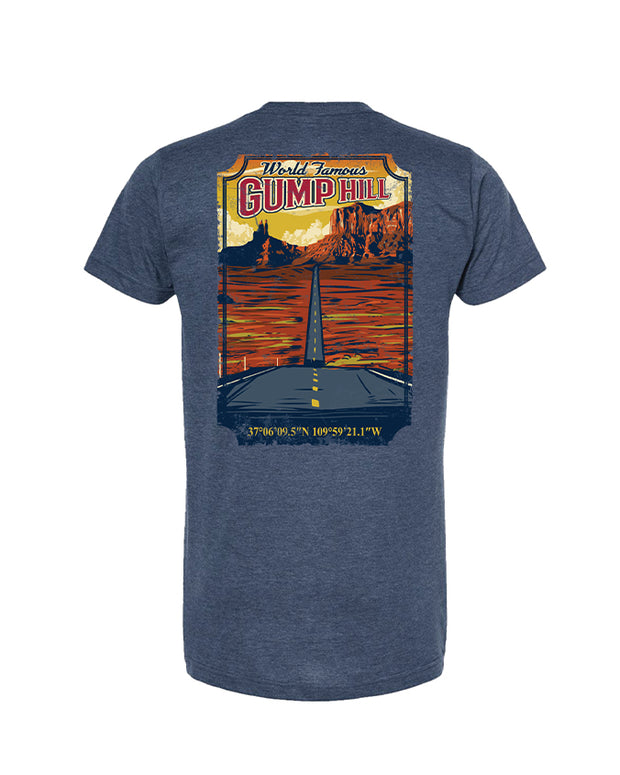 “World Famous Gump Hill” at the top in yellow and red font. Below is an illustration of a hill with trees silhouetted against an orange sky, suggesting either sunrise or sunset. In the foreground, there are two crossed canoe paddles above a body of water reflecting the sky’s colors. At the bottom of the design, coordinates “37°40’35"N 109°33’31"W” are displayed in blue text