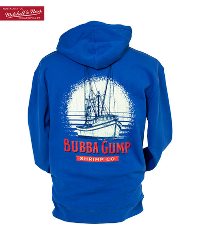 Back of royal blue bubba gump hoodie with back white and red graphics. Graphic features a boat and large exaggerated sun behind the ship with a splattered design. Below the ship graphics are the words "bubba gump shrimp co." Top left maroon tag that reads "Nostalgia Co. Mitchell & Ness Philadelphia, PA."