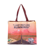 A tote bag with a printed design featuring a quote, ‘I JUST FELT LIKE RUNNING,’ from the movie Forrest Gump. Below the quote is an illustration of Forrest Gump running on a road that stretches across a landscape with greenery and hills in the background. The bottom of the bag displays the Bubba Gump Shrimp Co. logo along with their website address, www.bubbagump.com.