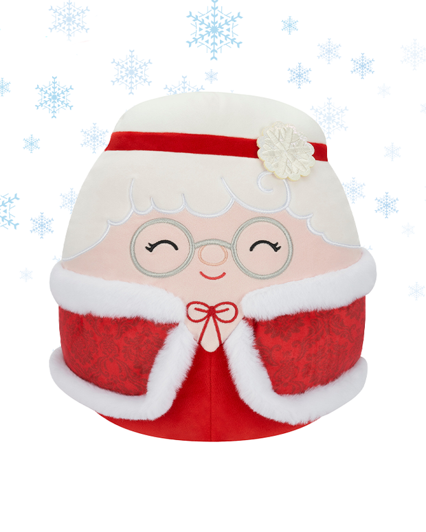 The image features a plush toy designed to resemble Mrs. Claus, wearing a red outfit with white fluffy trim, round glasses, and a snowflake flower on her hat. 