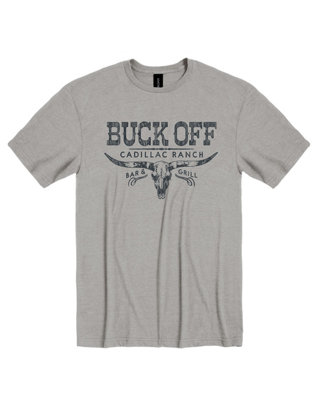 The image depicts a gray t-shirt with centered black and white text and graphics. The text reads “BUCK OFF” in large, bold letters at the top, followed by “CADILLAC RANCH” in a slightly smaller font. Below this is “BAR & GRILL” in a smaller, uppercase font. At the center is a stylized graphic of a bull’s skull with large horns. The t-shirt is displayed against a plain white background. 