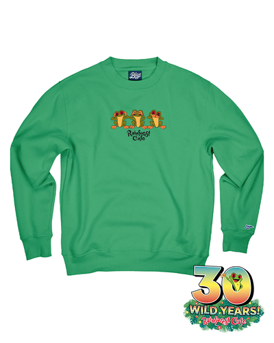 A green crewneck sweatshirt is displayed, featuring a central graphic of three colorful frogs. Below the frogs, the text ‘Rainforest Cafe’ is written in yellow. The sweatshirt has ribbed collar, cuffs, and hem, and in the bottom right corner, there’s a ‘30 WILD YEARS! Rainforest Cafe’ logo with a tree frog coming out the 0.