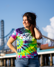 female model with pier background wearing Tie-dye designed tee that reads "no worries, I've got crabs" and "Joe's Crab Shack" underneath it.