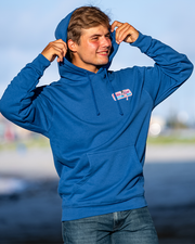 male model placing hood on. royal blue bubba gump hoodie with left chest blue, white, and red Bubba Gump rectangular logo patch. 