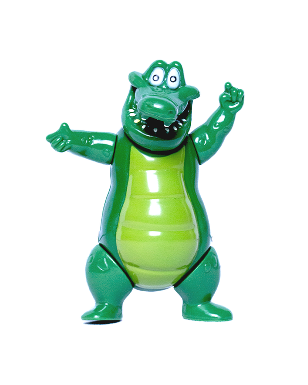 A green toy figure of a cartoonish crocodile standing upright with its arms open, showcasing a friendly and playful demeanor. The crocodile is glossy green with lighter shades on its belly, big white eyes with black pupils, and an open mouth with white teeth, giving it an inviting appearance. The toy’s upright stance and outstretched arms suggest it’s ready for a hug or eager to play.