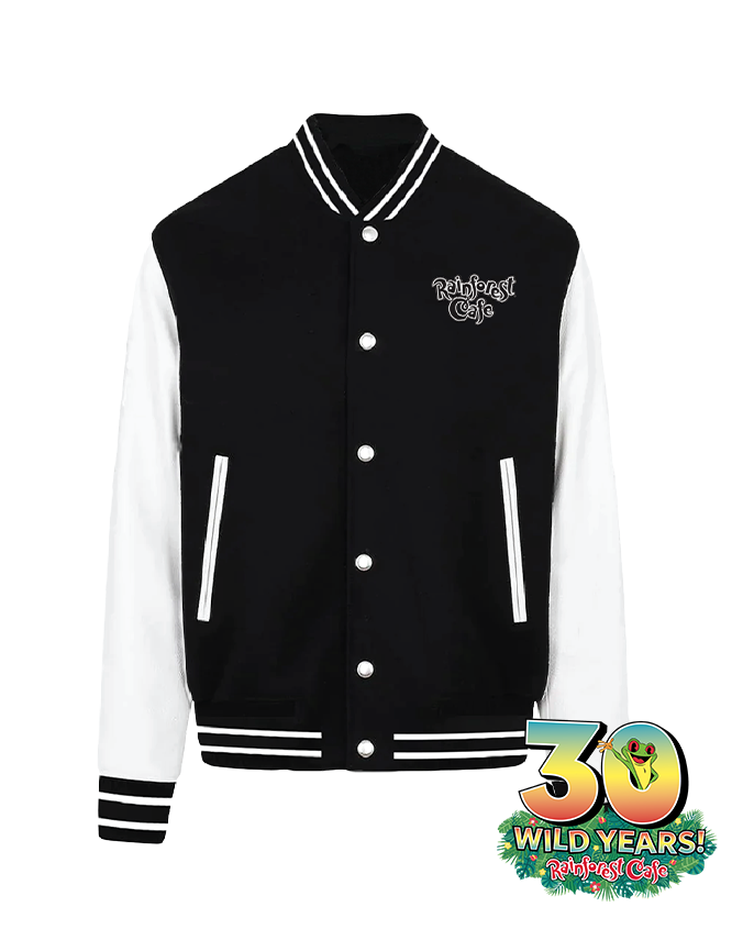 A black and white varsity jacket with a ribbed collar, cuffs, and waistband. The jacket has white leather sleeves, a black torso, and features white snap buttons down the front. On the left chest area, there is an embroidered patch that reads “Rainforest Cafe” in cursive script. On bottom, right corner is a logo with text reads “30 WILD YEARS,” indicating an anniversary celebration. Below the main text, additional small text reads “Rainforest Cafe.”