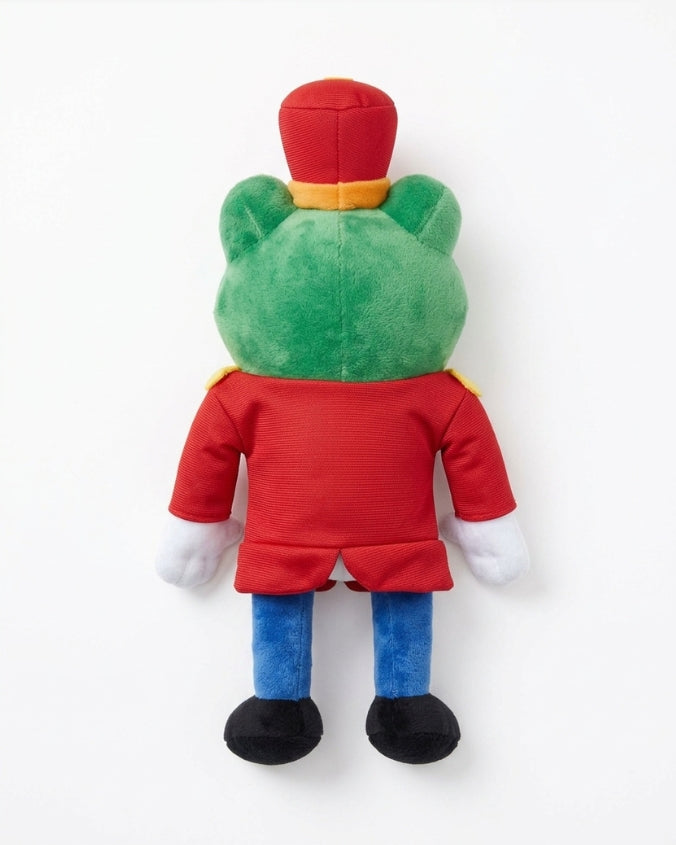 A plush toy of a frog character seen from the back, wearing a red uniform, blue pants, and a red hat with a yellow band, on a white background.