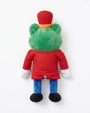 A plush toy of a frog character seen from the back, wearing a red uniform, blue pants, and a red hat with a yellow band, on a white background.