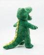 A green plush alligator toy standing on a white studio background, with yellow spikes along its back and tail, white teeth, and a small red tongue.