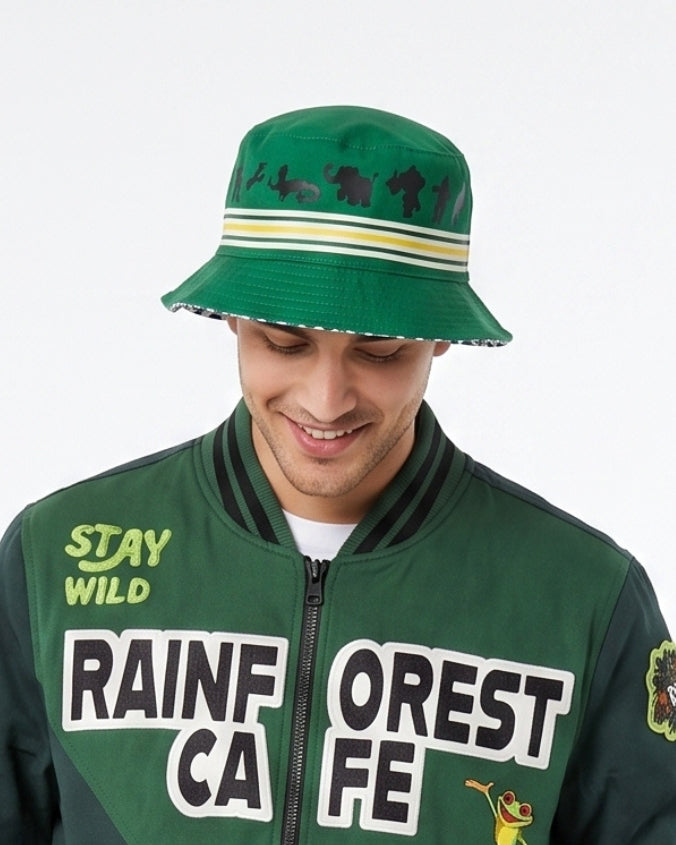 A man wearing a green bucket hat with black animal silhouettes and a green bomber jacket with 'RAIN FOREST CAFE' and 'STAY WILD' graphics, against a plain white background.