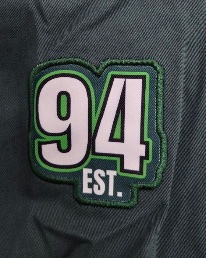 Patch with '94 EST.' on a dark fabric background