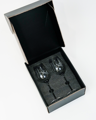 A pair of elegant wine glasses neatly packaged in a black box with a grey interior, suggesting a sophisticated gift or a set ready for a special occasion.