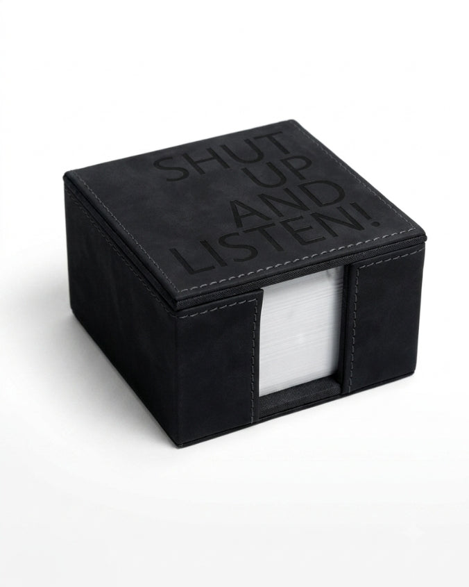 A black square box-shaped tissue holder or napkin dispenser with the words 'SHUT UP AND LISTEN!' embossed on the lid, shown on a clean white background.