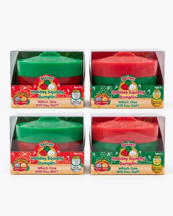 Four boxed pairs of Secret Santa holiday squishy dumplings on a white background. The packages contain either green or red dumplings, and each package has a clear plastic window with a colorful retail label reading 'Holiday Squishy Dumpling' and 'Which One Will You Get?'.