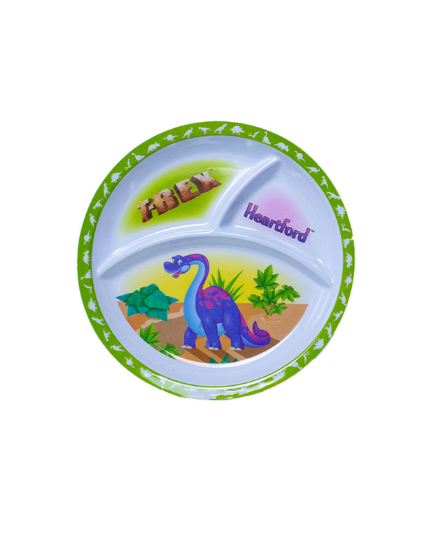 A children’s divided plate with three sections. The largest section at the bottom shows a colorful illustration of a blue dinosaur with purple spots, standing among green foliage. Above this, two smaller sections contain the words “T-REX” in brown lettering on a light background and “Heartford” in purple lettering on a blue background, respectively. The rim of the plate is decorated with a pattern of green leaves and small yellow dots.