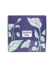 A blue box adorned with light blue outlined illustrations of leaves and flowers, featuring a central label with the ‘Rainforest Cafe’ logo. A small, peaceful illustration of a sleeping elephant and tree frog on one of the flowers adds a charming touch.