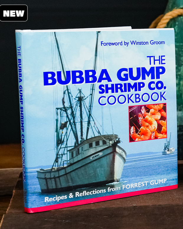 The BUBBA GUMP SHRIMP CO. COOKBOOK: A cookbook with a blue and white cover featuring a shrimp boat at sea. The title is displayed in bold blue letters, and there’s a smaller image of cooked shrimps. The book includes recipes and reflections from FORREST GUMP, with a foreword by Winston Groom.