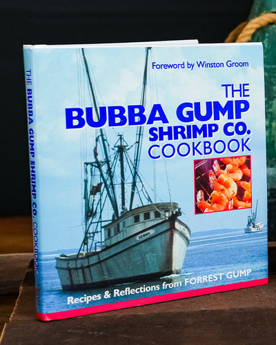 "the Bubba Gump Shrimp Co. Cookbook". Cover image has a shrimping boat on the seat and in a square frame on center right, a close up of grilled shrimp.