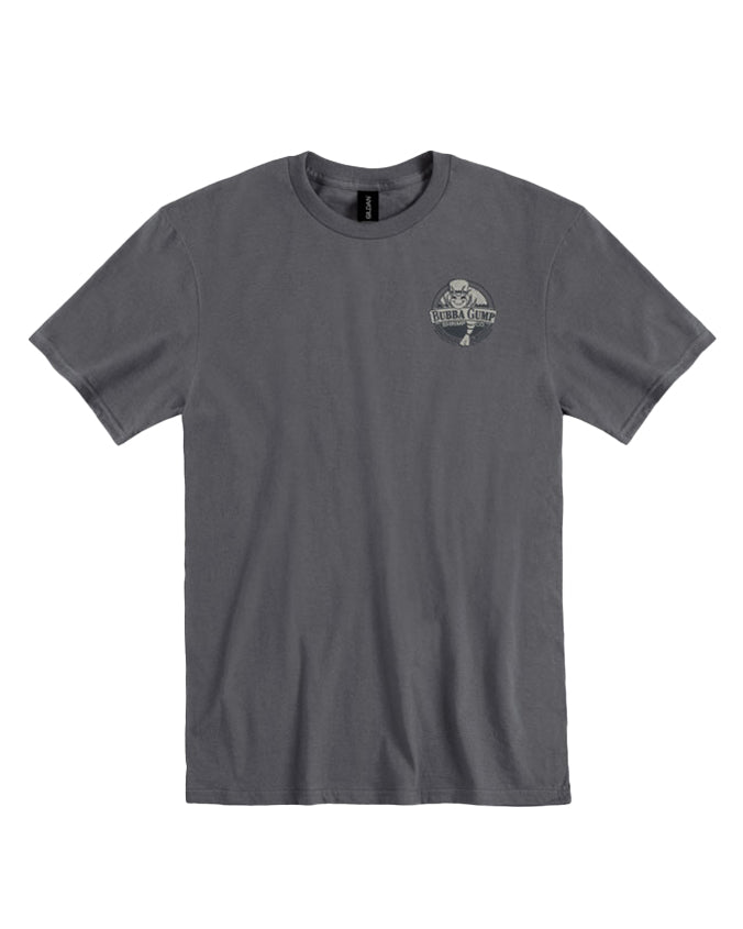 A plain gray t-shirt laid out flat against a white background. On the left chest area, there is a small circular logo or emblem with text and some design inside, but the details are not clear due to the size in the image. The t-shirt appears to be for adults.