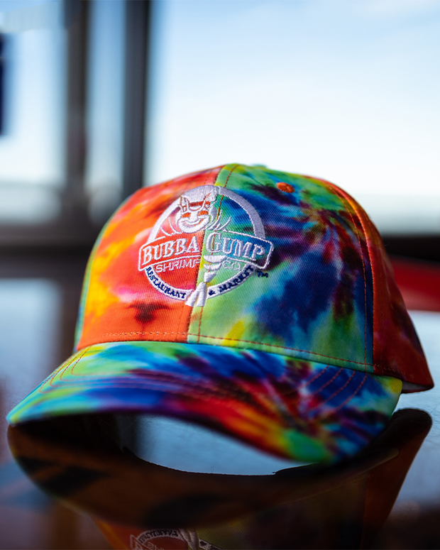 Vibrant tie dye cap with the Bubba Gump logo embroidered on the front in white, the words "Restaurant & Market" in blue.