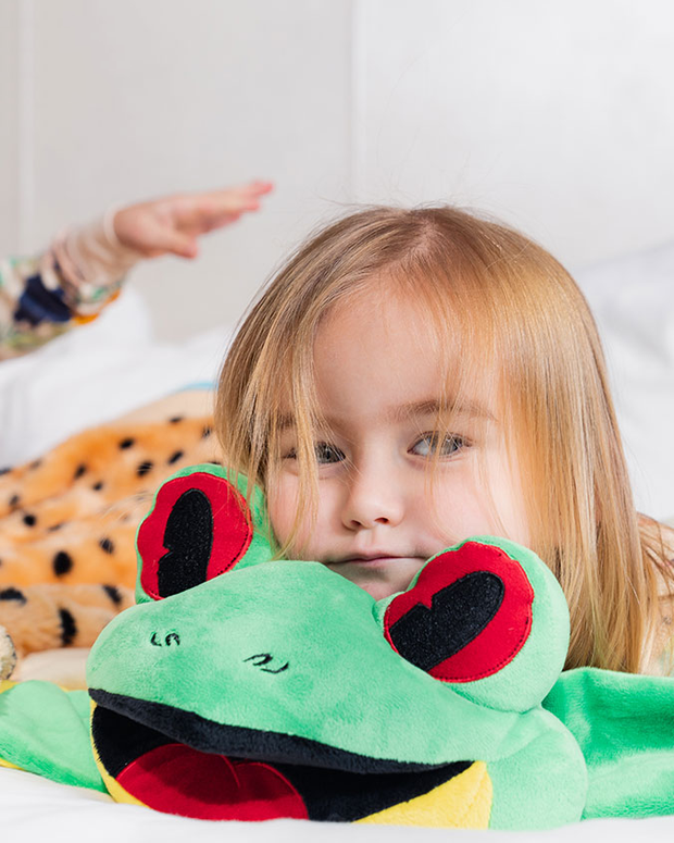 Little girl resting her head on top of Cha Cha the Frog plush blanket.