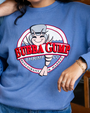 A woman wearing a blue sweatshirt featuring the Bubba Gump Shrimp Co. logo, smiling and showing off the playful design.
