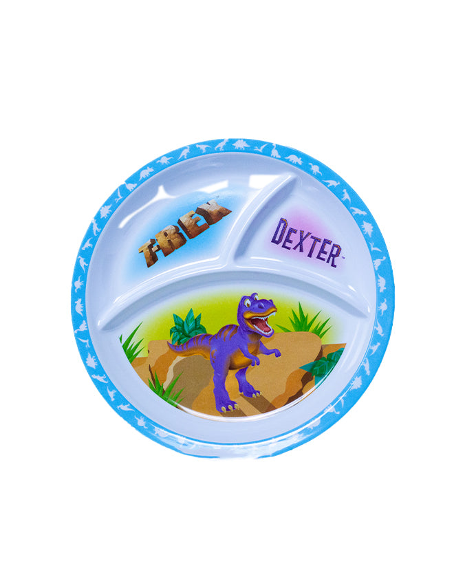 A children’s divided plate with three compartments. The largest section at the bottom features a graphic of a purple dinosaur standing on brown terrain with green foliage in the background. Above this, in a smaller section, there are three brown teddy bears. The smallest compartment contains the name ‘DEXTER’ written in white uppercase letters on a purple background. 