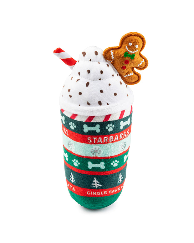 A plush toy designed to resemble a festive holiday-themed Starbucks Frappuccino. The toy features a white whipped cream top with sprinkles, a red and white striped straw, and an attached gingerbread man cookie. The cup is adorned with green, red, and white patterns including snowflakes, reindeer, and the text “Starbarks” along with “Ginger Bark Latte.”