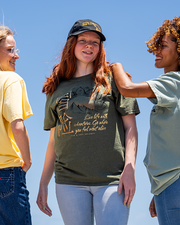 3 female models with sky view in background. left model wearing yellow tee. center model is wearing the Life Adventure tee, and right model has a light green tee.