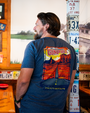 A person wearing a blue t-shirt featuring an illustration of a road leading to mountains, with the text "World Famous Gump Hill."