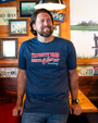 A person wearing a blue t-shirt with the quote "I'm pretty tired, I think I'll go home now" from Forrest Gump, standing in a cozy setting.