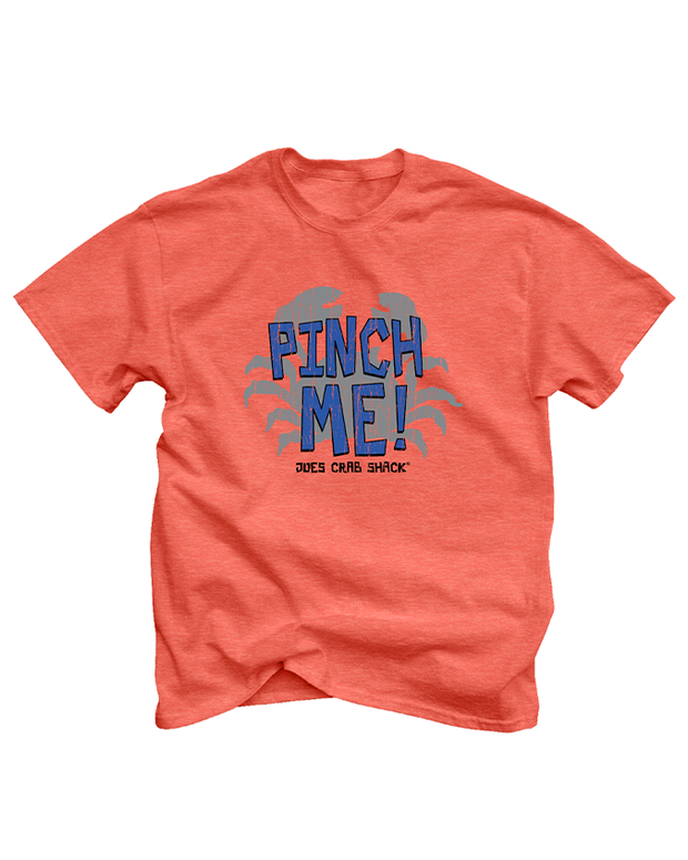 The image displays a coral red, short-sleeved t-shirt against a white background. It features a large blue graphic of a stylized crab with the text “PINCH ME!” in gradient blue above it, and “JOE’S CRAB SHACK” in smaller letters below. The design is central on the shirt.