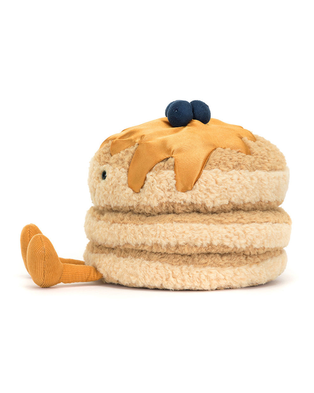 A side view of a plush 3-stacked pancake toy sitting against a white background with legs and feet out in front, including maple syrup and blueberries on top.