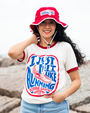 A person wears a vintage-style Bubba Gump t-shirt and a red bucket hat, posing against a rocky coastal backdrop.