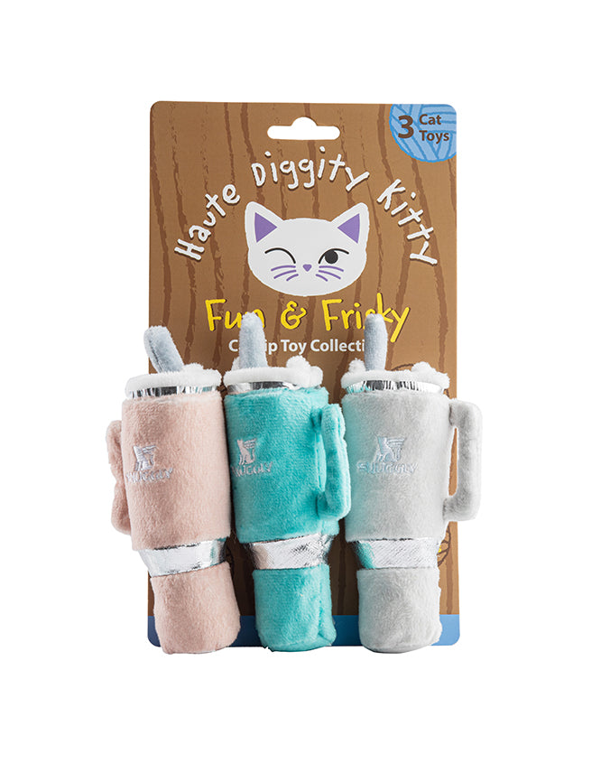 A product image featuring a set of three cat toys attached to a cardboard packaging. The packaging has a cartoon illustration of a cat’s face at the top with the text “Haute Diggity Kitty” written above and “Fun & Frisky Cat Toy Collection” below. Each toy resembles a stanley cup with varying shades of blue and pink.