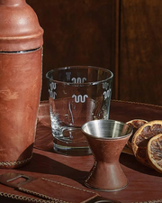 King Ranch whiskey glass with multiple running w's along the rim of the glass, pictured with a shaker and grapefruit slices.