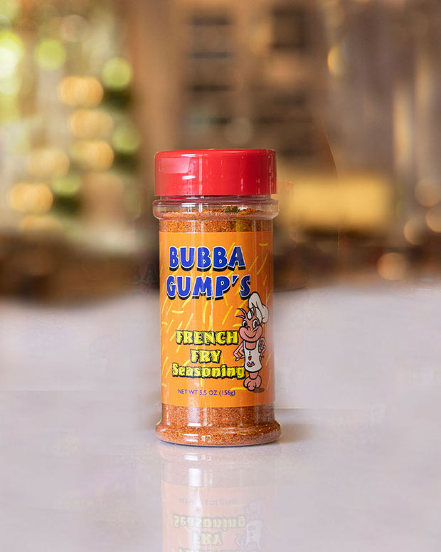 Bubba Gump’s Seafood French Fry Seasoning: A clear plastic container with a red cap, containing Bubba Gump’s French Fry  Seasoning. The label features colorful graphics and text, including the brand name, and the net weight (5.5 oz), and  a cartoon of  a shrimp with an apron and  chefs hat.