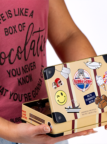 The image depicts a person holding a tablet with a case adorned with various stickers. Notably, there’s a smiling face sticker and another labeled “Bubba Gump Shrimp Co.” The person wearing a pink t-shirt with the text “LIFE IS LIKE A BOX OF CHOCOLATES YOU NEVER KNOW WHAT YOU’RE GONNA GET” in white letters. The overall theme seems related to the movie “Forrest Gump”.